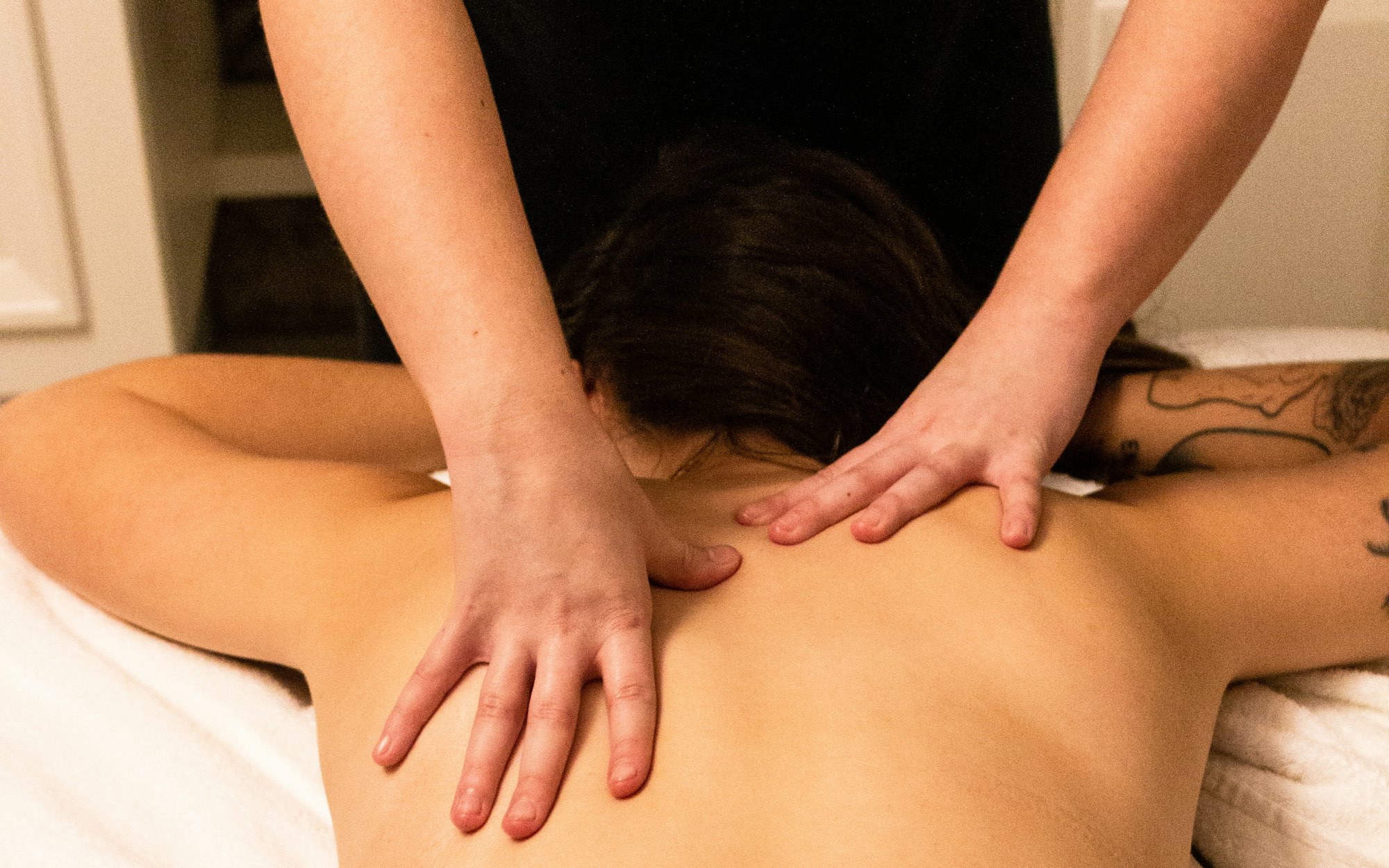 A therapist working along a client's shoulders during a massage